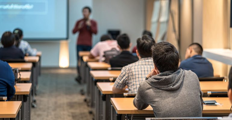 rear-view-audience-listening-asian-speaker-stage-meeting-room (1)